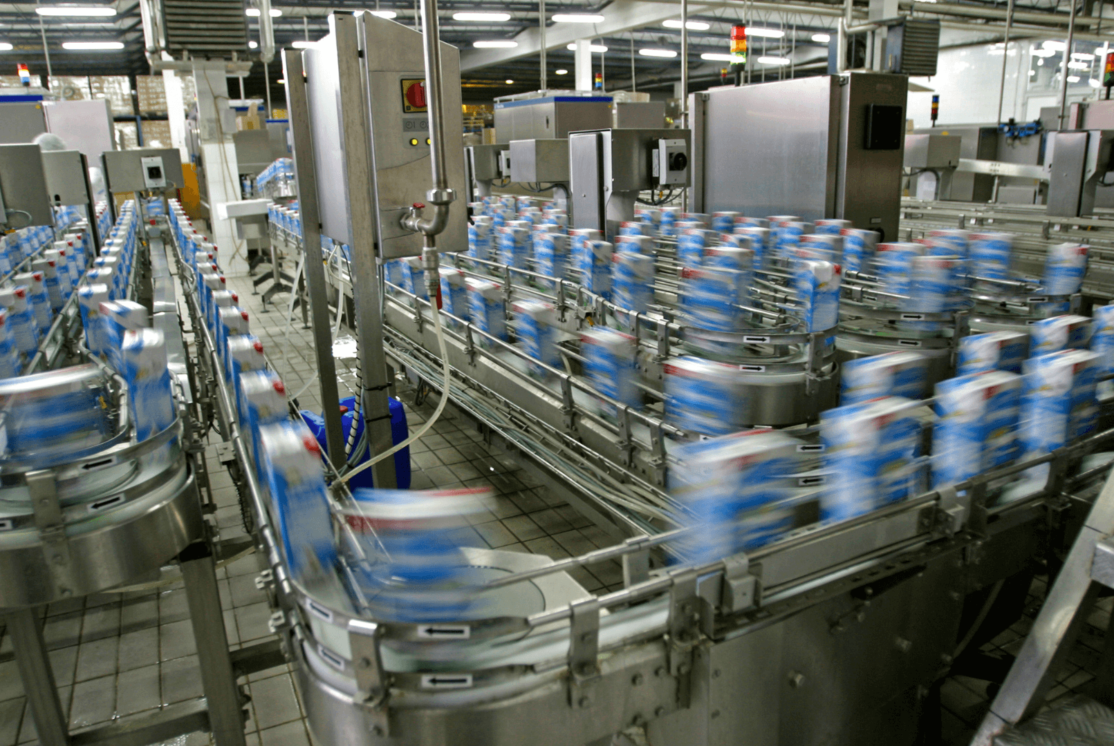 Embalagens em movimento sobre esteiras de aço inoxidável em linha de envase