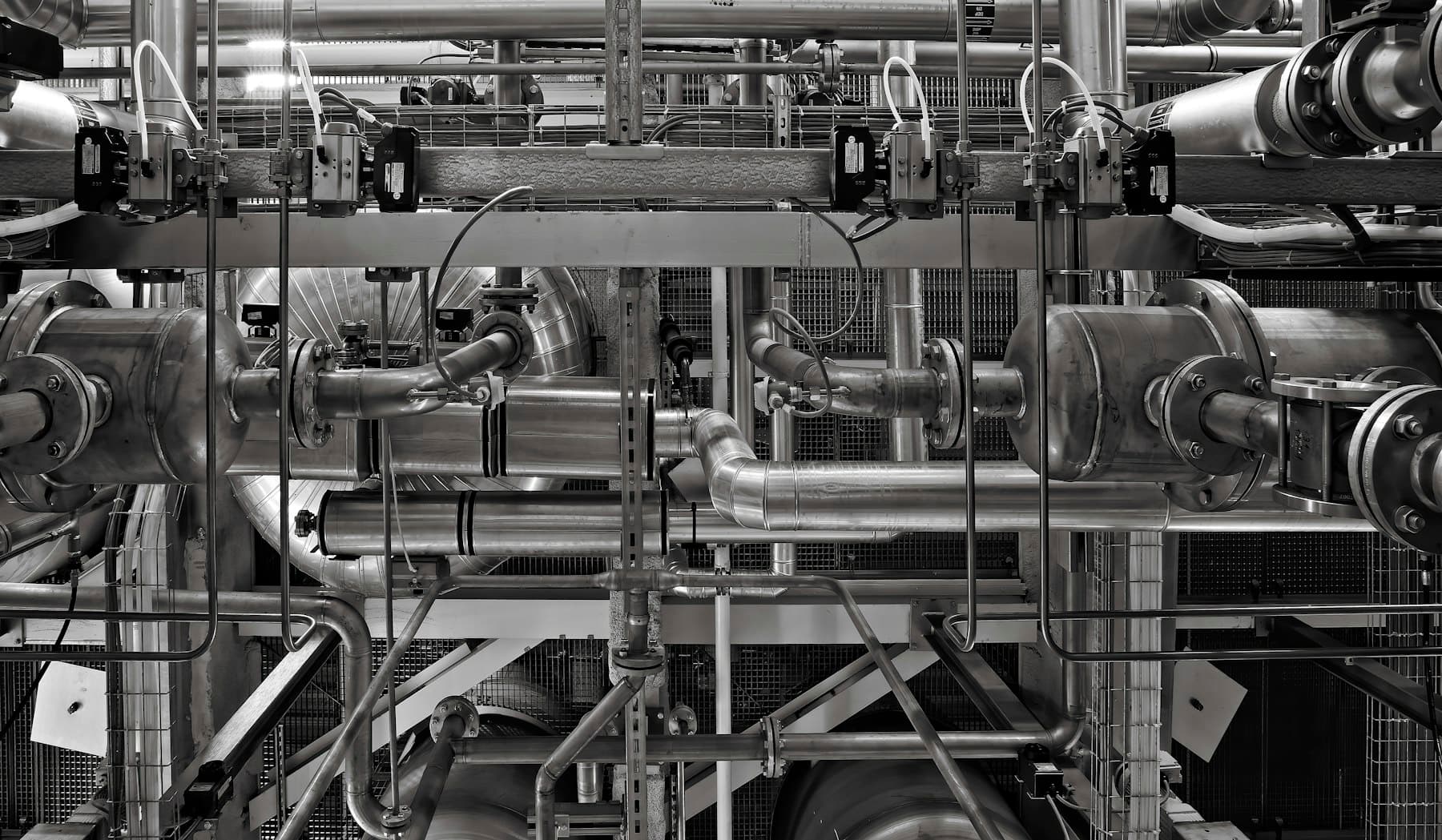 Tubulação, válvulas, vasos e atuadores de uma instalação industrial em preto e branco