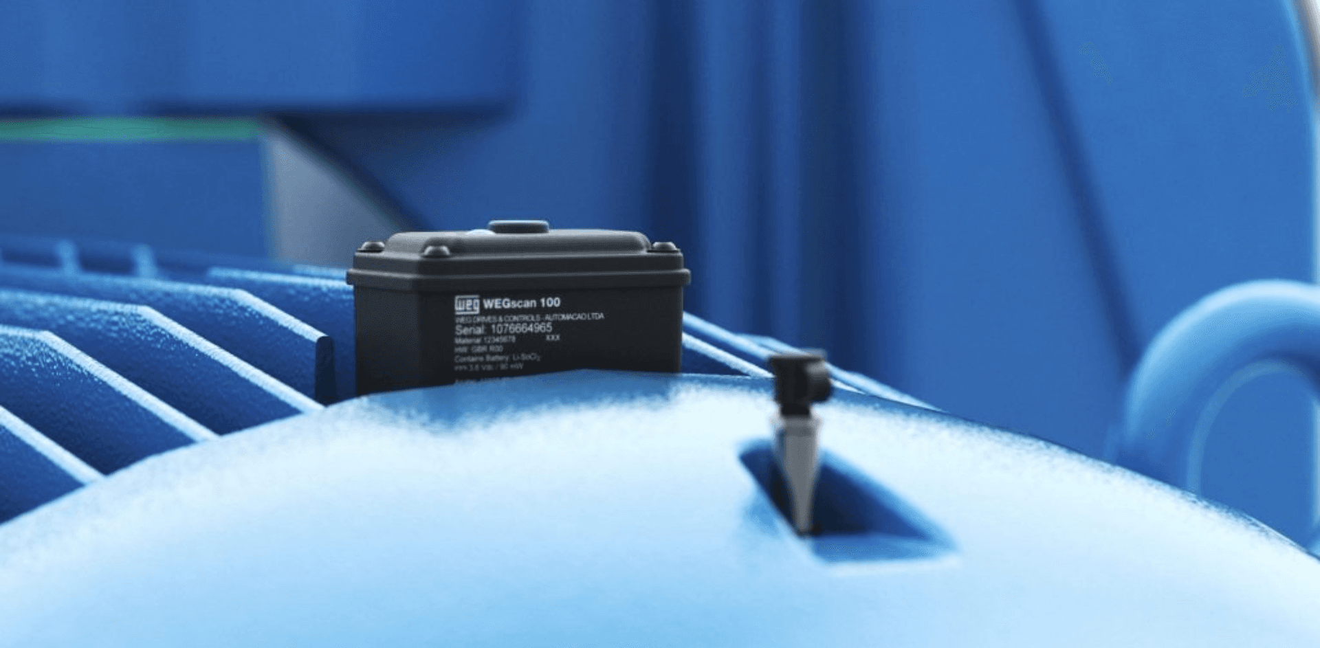Sensor de vibração e temperatura fixado sobre a carcaça aletada de um motor azul