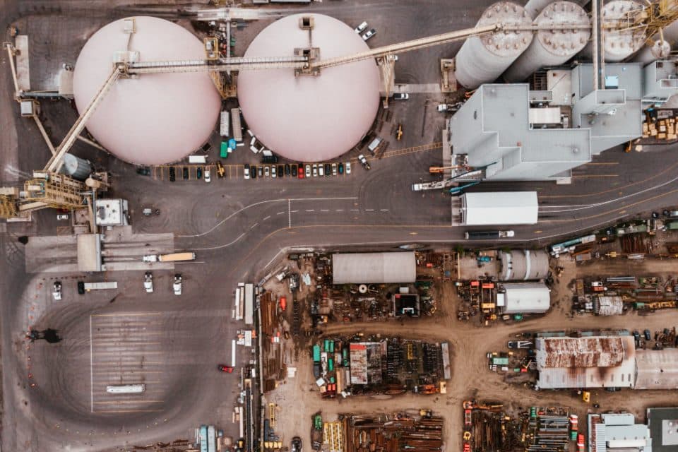 Vista aérea de um pátio industrial com dois tanques esféricos, caminhões e área de estocagem